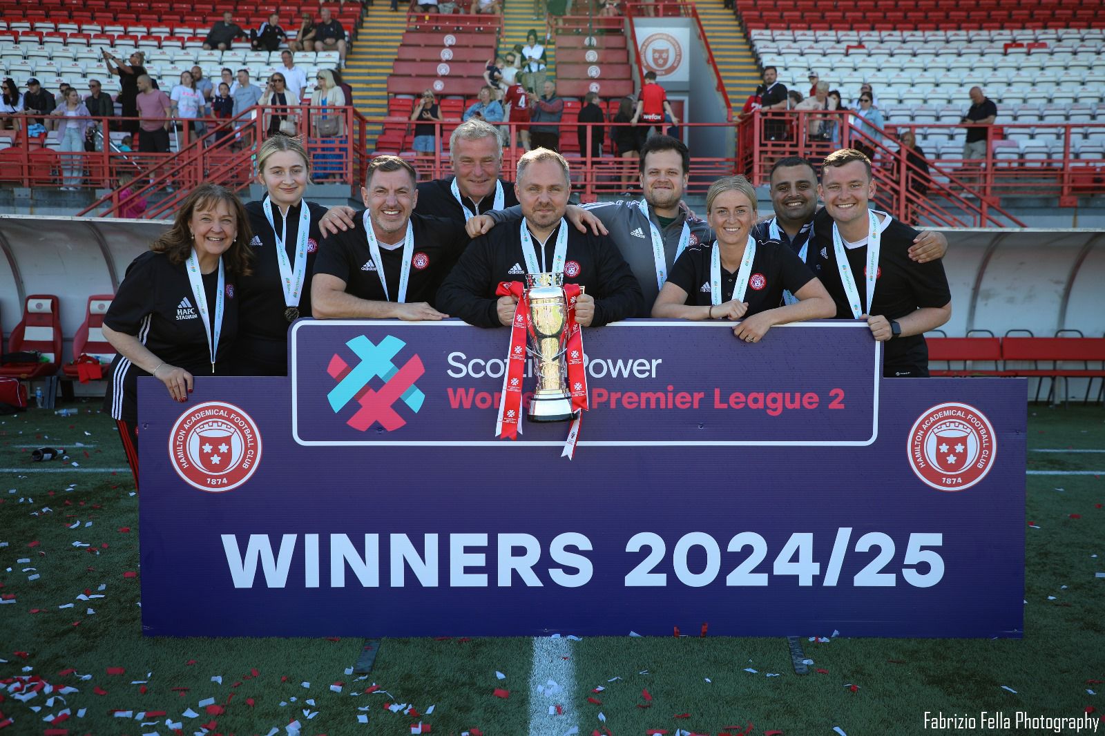 Kevin Middleton with the Hamilton Academical Women coaching staff lifting the Scottish Women's Premier League 2 trophy, winners 2024/25.